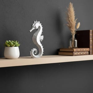 Modernes Seepferdchen als elegante Skulptur im minimalistischen Stil. Maritime Dekoration aus 3D Druck Kunststoff für Badezimmer, Wohnzimmer, Regal oder Sideboard. Stilvolle Tierfigur mit klarer Formensprache passend zu Küstenstil, Japandi oder moderner Einrichtung.
Dekorative Seepferdchen Figur als maritime Wohnraumdeko mit moderner geometrischer Optik. Ideal für Bad, Schlafzimmer oder Eingangsbereich.