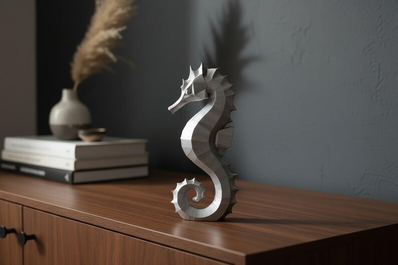 Modernes Seepferdchen als elegante Skulptur im minimalistischen Stil. Maritime Dekoration aus 3D Druck Kunststoff für Badezimmer, Wohnzimmer, Regal oder Sideboard. Stilvolle Tierfigur mit klarer Formensprache passend zu Küstenstil, Japandi oder moderner Einrichtung.
Dekorative Seepferdchen Figur als maritime Wohnraumdeko mit moderner geometrischer Optik. Ideal für Bad, Schlafzimmer oder Eingangsbereich.