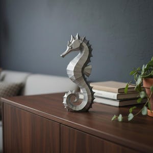 Modernes Seepferdchen als elegante Skulptur im minimalistischen Stil. Maritime Dekoration aus 3D Druck Kunststoff für Badezimmer, Wohnzimmer, Regal oder Sideboard. Stilvolle Tierfigur mit klarer Formensprache passend zu Küstenstil, Japandi oder moderner Einrichtung.
Dekorative Seepferdchen Figur als maritime Wohnraumdeko mit moderner geometrischer Optik. Ideal für Bad, Schlafzimmer oder Eingangsbereich.