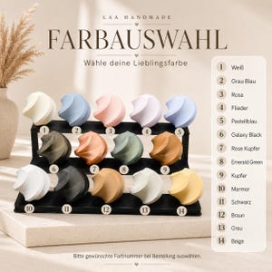 May include: A display of decorative swirl-shaped objects in various colors, including white, blue, pink, and green. The text "FARBAUSWAHL" and "W&auml;hle deine Lieblingsfarbe" are visible. Numbers 1-14 correspond to color options.