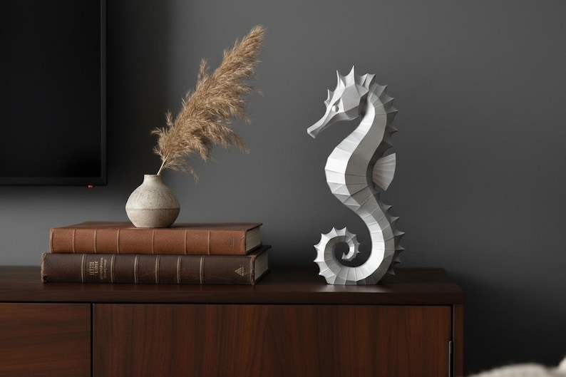 Modernes Seepferdchen als elegante Skulptur im minimalistischen Stil. Maritime Dekoration aus 3D Druck Kunststoff für Badezimmer, Wohnzimmer, Regal oder Sideboard. Stilvolle Tierfigur mit klarer Formensprache passend zu Küstenstil, Japandi oder moderner Einrichtung.
Dekorative Seepferdchen Figur als maritime Wohnraumdeko mit moderner geometrischer Optik. Ideal für Bad, Schlafzimmer oder Eingangsbereich.