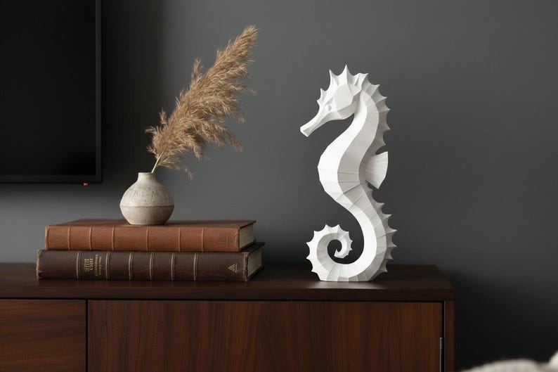 Modernes Seepferdchen als elegante Skulptur im minimalistischen Stil. Maritime Dekoration aus 3D Druck Kunststoff für Badezimmer, Wohnzimmer, Regal oder Sideboard. Stilvolle Tierfigur mit klarer Formensprache passend zu Küstenstil, Japandi oder moderner Einrichtung.
Dekorative Seepferdchen Figur als maritime Wohnraumdeko mit moderner geometrischer Optik. Ideal für Bad, Schlafzimmer oder Eingangsbereich.