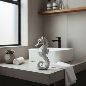 Modernes Seepferdchen als elegante Skulptur im minimalistischen Stil. Maritime Dekoration aus 3D Druck Kunststoff für Badezimmer, Wohnzimmer, Regal oder Sideboard. Stilvolle Tierfigur mit klarer Formensprache passend zu Küstenstil, Japandi oder moderner Einrichtung.
Dekorative Seepferdchen Figur als maritime Wohnraumdeko mit moderner geometrischer Optik. Ideal für Bad, Schlafzimmer oder Eingangsbereich.