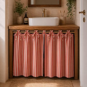 May include: A wooden vanity with a white rectangular sink and a gold faucet. Red and white striped curtains hang below the countertop, tied with bows. A small plant and a soap dispenser sit on the counter.