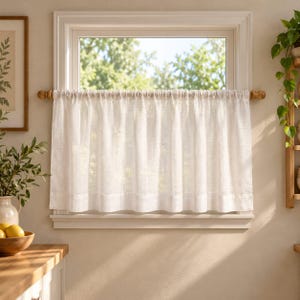 Puede incluir: Una cortina de caf&eacute; blanca semitransparente cuelga de una barra de madera montada dentro del marco de una ventana. La cortina presenta un encabezado de bolsillo para barra simple y un dobladillo recto, permitiendo que la luz natural pase.