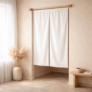 May include: White fabric door curtain suspended from a wooden rod. The curtain is split down the middle, offering a view of the room behind. A vase with dried pampas grass is near a window with sheer white curtains.