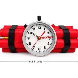 Puede incluir: Un artículo novedoso que se asemeja a la dinamita, con cuatro tubos cilíndricos rojos sujetos con correas negras. Un reloj con borde plateado con la palabra "BOOM" está centrado, mostrando la hora. El artículo mide 36,8 cm de ancho y 17,8 cm de alto.