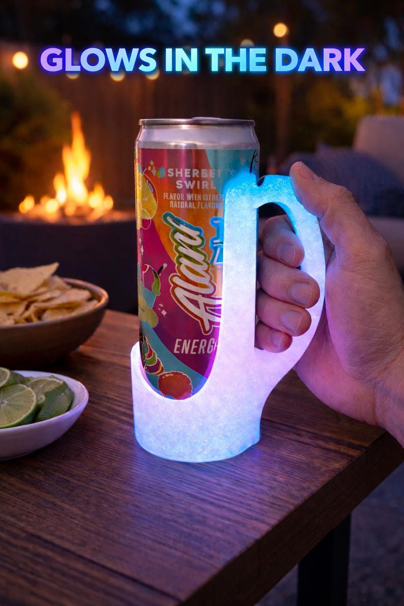 May include: A glowing, illuminated drink holder with a handle, holding a can of "Alani Energy" drink. The can features a colorful design with the words "Sherbet Swirl". The words "Glows in the Dark" are above the drink holder.