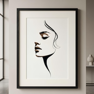 May include: A framed wall art print featuring a minimalist black line drawing of a side profile of a face. The illustration uses fluid black lines to define the hair, eyelashes, and jawline, with subtle brown shading on the eyelid and lips.