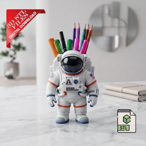 May include: A white astronaut-shaped desk organizer holding pens and pencils. The astronaut has a black visor and the American flag on the shoulder. The image includes a red banner that says "3D STL FILES DIGITAL DOWNLOAD".