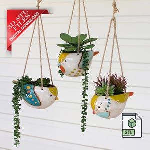 May include: Three hanging bird-shaped planters with succulents. The ceramic pots are white, yellow, and blue, with orange beaks and decorative dots. They hang from twine cords. A red corner tag reads "3D STL FILES DIGITAL DOWNLOAD".