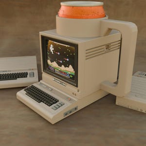 May include: A beige computer-shaped mug featuring a screen displaying a pixelated video game, a keyboard base, and a large side handle. An orange circular container sits on top of the monitor. The text Coaster 64 is printed on the front panel.