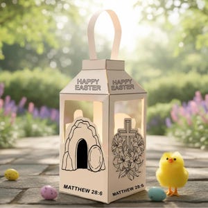 以下が含まれることがあります： 「HAPPY EASTER」の文字と聖書の詩篇マタイ28:6が書かれた、持ち手付きの白い紙製のランタン。ランタンには、墓と花の十字架の切り抜きデザインがあります。黄色いひよことイースターエッグが前景にあります。