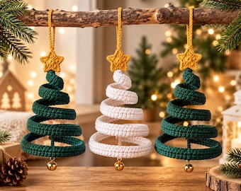 May include: Three hanging Christmas tree ornaments made of crocheted yarn. Two trees are dark green and one is white, each topped with a yellow crocheted star and featuring a small gold bell hanging from the bottom of the spiral structure.