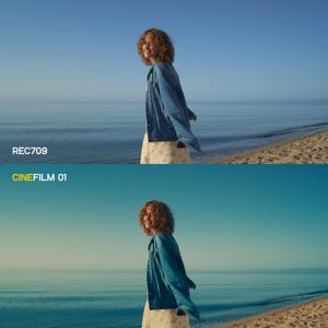 May include: A woman in a denim jacket and floral dress stands on a beach with the sea in the background. The text "REC709" and "CINEFILM 01" are visible in the image. The sky is a clear blue.