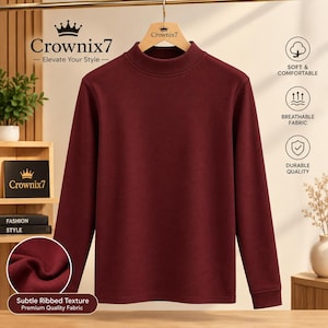 May include: A long-sleeve mock neck shirt in a solid deep burgundy colour. The shirt features a subtle ribbed texture and is displayed on a wooden hanger branded with the Crownix7 logo. The design is plain with long sleeves.
