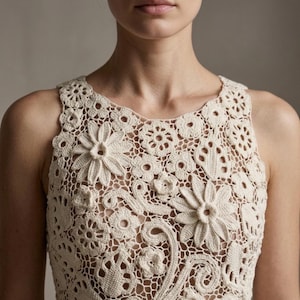 May include: A cream-coloured, sleeveless crochet top with a floral design. The top has a round neckline and is decorated with various sizes of crocheted flowers and decorative patterns. The intricate openwork creates a delicate and textured appearance.