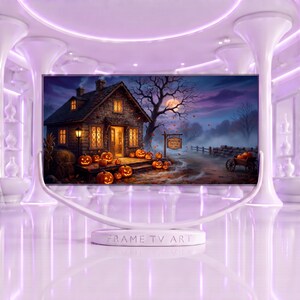 Pode incluir: Uma tela digital num suporte branco com a etiqueta FRAME TV ART, mostrando uma casa de pedra à noite com abóboras iluminadas na varanda, uma árvore nua, lua cheia e uma placa com os dizeres THE PUMPKIN PATCH EST 1892.