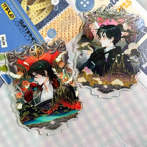 May include: Two clear acrylic standees featuring anime-style characters in ornate frames. One character holds a red rose, while the other is set against a dark, gothic-inspired background with a castle silhouette. Both feature vibrant, detailed artwork.
