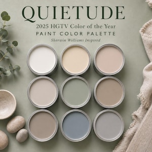 Op de afbeelding: Negen verfpotten met deksels eraf, met een palet van neutrale kleuren. De afbeelding bevat de tekst "QUIETUDE 2025 HGTV Color of the Year PAINT COLOR PALETTE Sherwin Williams Inspired." Decoratieve elementen zijn een kleine kom, stenen en eucalyptus.