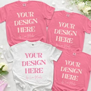 Puede incluir: Tres camisetas de manga corta, una blanca y tres rosas, cada una con el texto YOUR DESIGN HERE en una fuente serif negrita, seguido del texto en cursiva by Lion Mocks. Las camisetas est&aacute;n dispuestas en una composici&oacute;n plana.