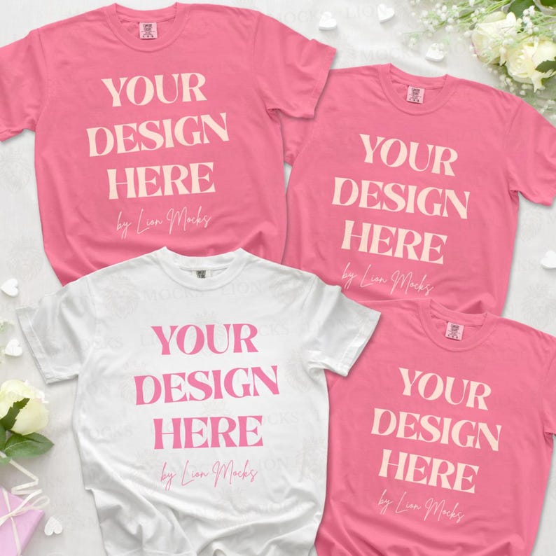 Puede incluir: Tres camisetas de manga corta, una blanca y tres rosas, cada una con el texto YOUR DESIGN HERE en una fuente serif negrita, seguido del texto en cursiva by Lion Mocks. Las camisetas est&aacute;n dispuestas en una composici&oacute;n plana.