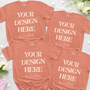 Puede incluir: Cuatro camisetas de manga corta de color coral dispuestas en grupo. Cada camiseta presenta el texto blanco "YOUR DESIGN HERE" en una fuente serif en negrita, seguido del texto en cursiva "by Lion Mocks" y una peque&ntilde;a etiqueta rectangular en el cuello.