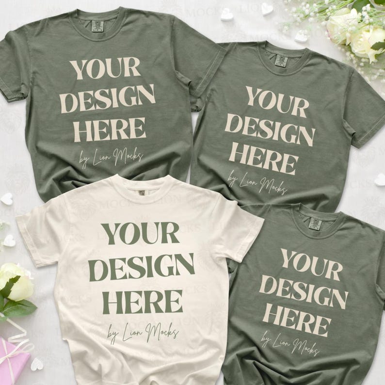 Puede incluir: Tres camisetas de manga corta en colores verde oliva y crema. Cada camiseta presenta el texto "YOUR DESIGN HERE" en una fuente serif negrita, seguido de la escritura cursiva "by Lion Mocks" impresa en el centro de la prenda.