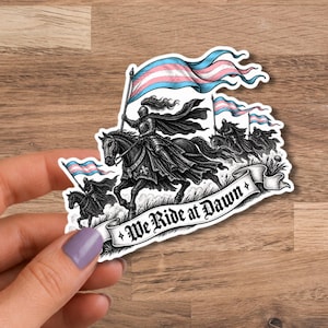 Könnte beinhalten: Ein gestanzter Aufkleber mit einer schwarz-weißen Illustration von gepanzerten Rittern zu Pferd, die hellblau, rosa und weiß gestreifte Flaggen tragen. Ein Banner am unteren Rand zeigt den Text "We Ride at Dawn" in dekorativer Schrift.