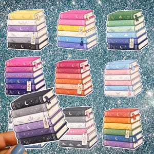 Può includere: Una collezione di nove adesivi, ognuno raffigurante una pila di cinque libri. I libri sono illustrati in vari colori pastello e vivaci, decorati con motivi celesti come lune, stelle e disegni floreali, e includono piccoli segnalibri.