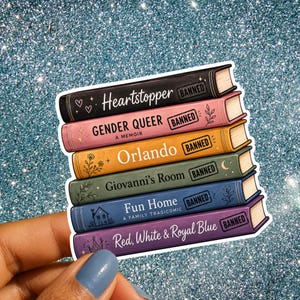 Pode incluir: Um adesivo com uma pilha de seis livros com as lombadas rotuladas como Heartstopper, Gender Queer, Orlando, Giovanni's Room, Fun Home e Red, White & Royal Blue. Cada lombada inclui um carimbo retangular com a palavra BANNED.