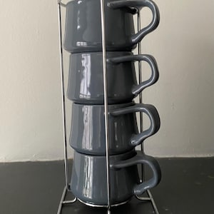 May include: A set of three ceramic mugs with a speckled, matte finish. The mugs are in cream, light grey, and dark grey. Each mug has a simple, minimalist design, ideal for coffee or tea.