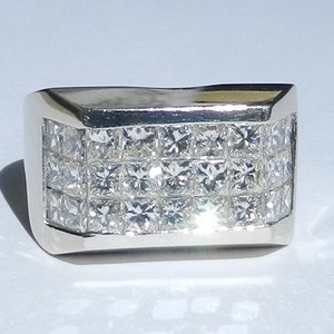 May include: A silver ring with a wide band set with multiple rows of square-cut diamonds.