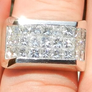 May include: A silver band ring with a rectangular setting featuring multiple rows of small, square-cut diamonds.
