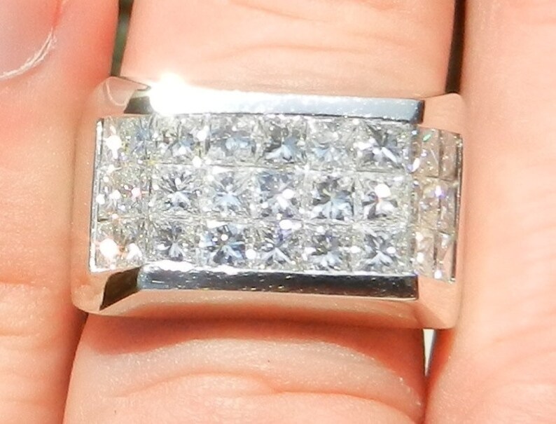 May include: A silver band ring with a rectangular setting featuring multiple rows of small, square-cut diamonds.