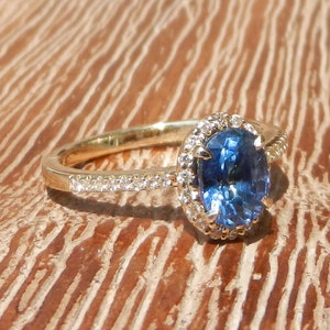 May include: A gold ring with a blue oval sapphire surrounded by a halo of small diamonds.