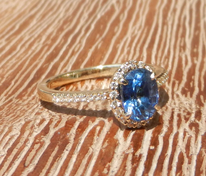 May include: A gold ring with a blue oval sapphire surrounded by a halo of small diamonds.