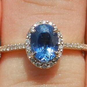 May include: A gold ring with a large oval blue sapphire surrounded by a halo of smaller diamonds.