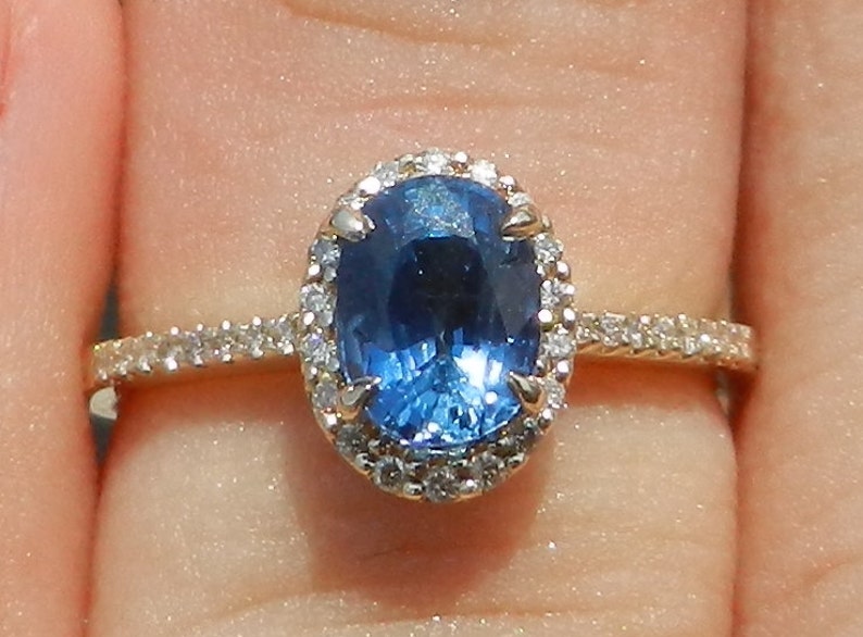 May include: A gold ring with a large oval blue sapphire surrounded by a halo of smaller diamonds.