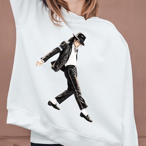 May include: White hoodie featuring a graphic of a person in a black suit, hat, and sunglasses, performing a dance move. The graphic is centered on the front of the hoodie. The hoodie has a drawstring hood and long sleeves.