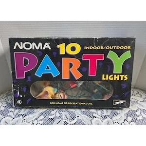 Puede incluir: Una caja de cartón rectangular negra para Noma 10 Party Lights, con texto colorido y una ventana de plástico transparente que revela una cadena de luces en el interior. La caja incluye el texto Indoor/Outdoor y For Home or Recreational Use.