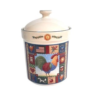 May include: A cream-colored ceramic canister with a lid, featuring a central illustration of a colorful rooster surrounded by a patchwork border of small icons including an American flag, a tea cup, a heart, a cow, an apple, and text.