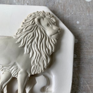May include: A white plaster mold of a lion's head with detailed mane and facial features.
