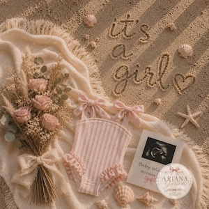 May include: A light pink and white striped baby romper with ruffled leg openings and shoulder bows, displayed on a cream fringed blanket with a dried flower bouquet, a baby ultrasound print, and the sand-written text it's a girl.