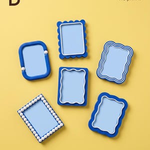 Può includere: Cinque cornici rettangolari blu e bianche con vari design dei bordi, inclusi motivi smerlati, ondulati e a perline. La lettera B e il testo You imagine it We print it sono visibili negli angoli in alto a sinistra e a destra dell'immagine.