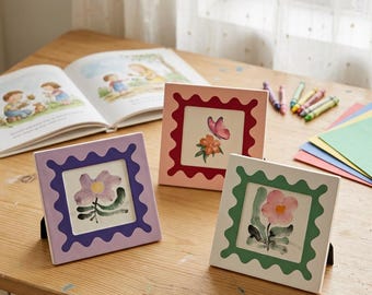 Marco de fotos cuadrado ondulado con bordes festoneados, decoración de mesa en tonos pastel, ideal para exhibir arte en la habitación infantil.