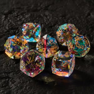 May include: A collection of seven iridescent, multi-faceted dice. Each die is a different shape, with gold-colored numbers. The dice have a rainbow effect, reflecting various colors. The dice are set against a dark, textured background.