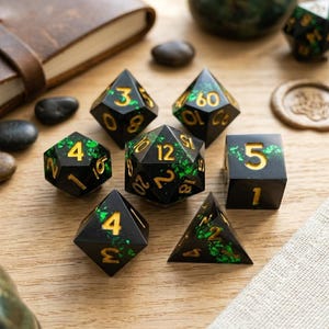 May include: A set of seven polyhedral dice in various shapes, including a d4, d6, d8, d10, d12, d20, and a percentile die. The dice are black with gold numbering and green accents. The dice are arranged on a wooden surface.