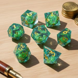 Puede incluir: Un conjunto de siete dados poliédricos con un diseño de purpurina verde y azul verdoso. Los dados tienen números dorados y están colocados sobre una superficie marrón claro. Para juegos de mesa.