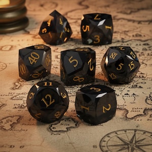 May include: Set of seven black polyhedral dice with gold numbering, designed for tabletop role-playing games. The dice are arranged on a map-themed surface, showcasing their various geometric shapes and numerical faces.